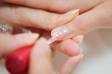 ネイリストにトップコートを塗ってもらっている女性の手のクローズアップ