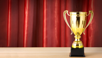 champion golden trophy on wood table with Red closed curtain background