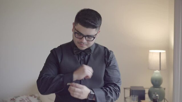 Groom fixing cufflinks on wedding day. Getting ready on wedding day.