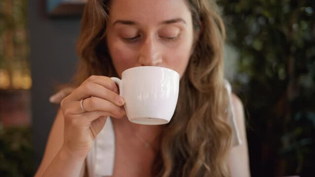 Woman drinking a cup of coffee at an italian restaurant, slow motion