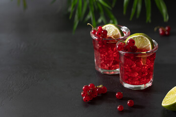 Redcurrant mojito in glasses with ice. Refreshing berry drink on black background