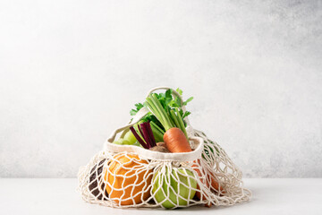 Vegetables and fruits in mesh bag on light background. Zero waste shopping concept