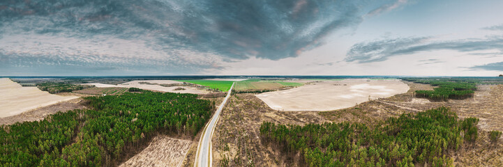 Fototapeta na wymiar Aerial View Of Highway Road Through Deforestation Area Landscape. Green Pine Forest In Deforestation Zone. Top View Of Field And Forest Landscape. Drone View. Bird's Eye View