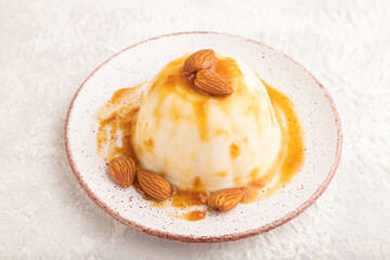 White milk jelly with caramel sauce on gray concrete, side view.
