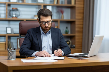 Fototapeta na wymiar Serious thinking businessman behind paper work, senior experienced boss working concentratedly sitting inside office at table, financier investor signing contract.
