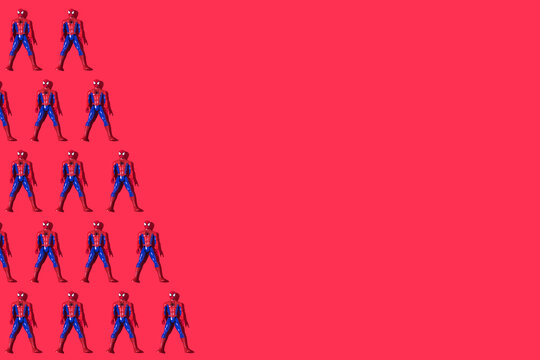 Pattern of Marvel and Sony spiderman dolls, on the left side, on a red background. Comic, superhero, spider, spider-man, mask and editorial concept.
