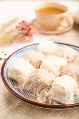 traditional arabic sweets pishmanie and a cup of green tea on white wooden,  side view, selective focus.