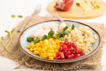 Mixed quinoa porridge, sweet corn and small sausages on white wooden, side view, selective focus.