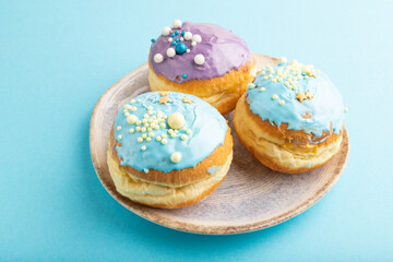Obraz na płótnie Canvas Purple and blue glazed donut on blue pastel, side view.