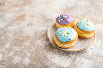 Purple and blue glazed donut on brown concrete, side view, copy space.