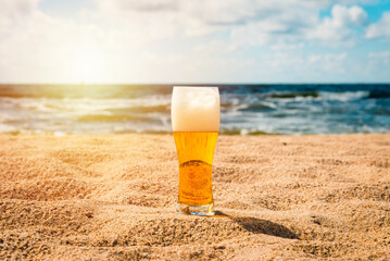 Cold beer on sand and beach background.Glass with light fresh beer or ale with water drops for...