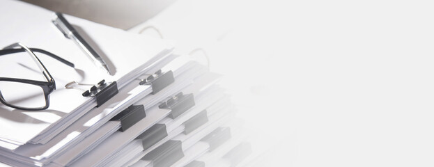 Stack of documents, eyeglasses and pen on table in office.
