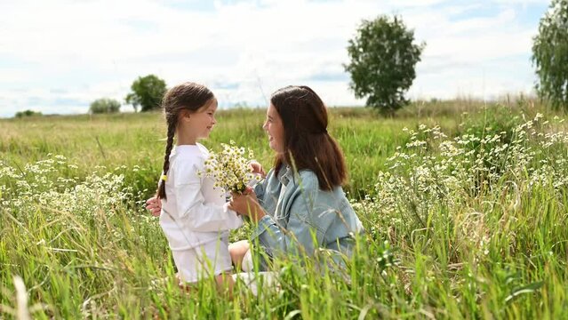 Mother and daughter embrace in a daisy field