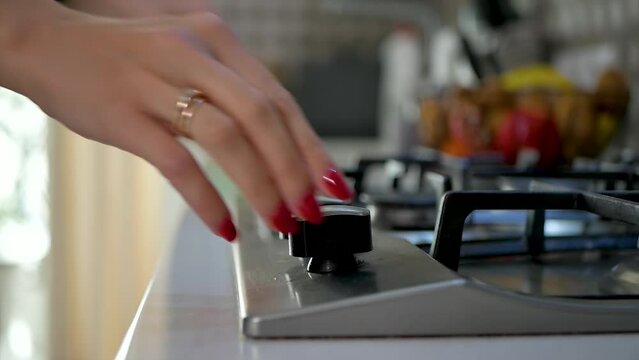 close-up of a woman's hand with a beautiful manicure lighting a gas stove for cooking the home comforts of the modern world igniting the gas using a permanent igniter