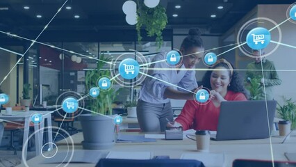 Animation of connected padlock and cart icons over diverse female colleagues discussing over laptop - Powered by Adobe