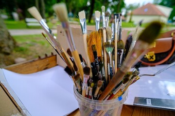 Fototapeta premium Close-up of used and cleaned brushes of various shapes and sizes, natural bristle brushes in a bucket, tools. Creative hobby, painter equipment background concept