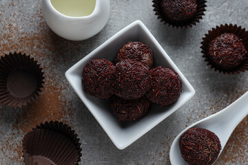 Brigadeiro in bowl and spoon on gray background, top view