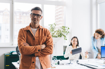 Pensive man with crossed arms looking away in office