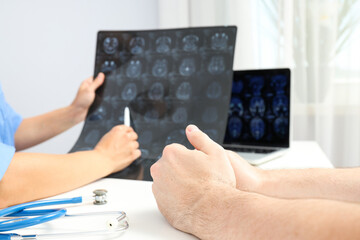 The doctor shows the tumor to the patient on MRI images of the head