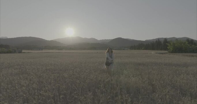 Chica andando por atardecer por el campo de trigo ( log footage )