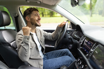 Young handsome man holding key of new car with winner gesture at street