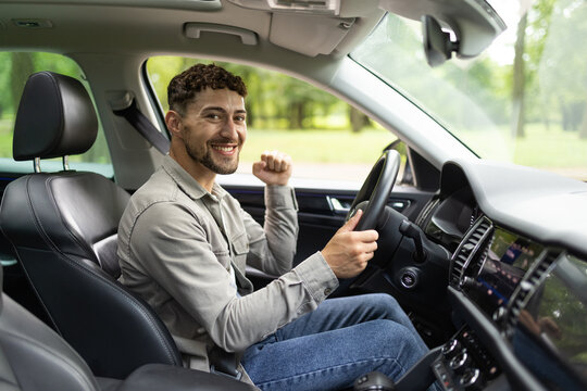Young man smiling happy doing ok sign driving car.