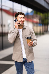Young urban businessman in the street talking on their smartphone and drinking coffee.