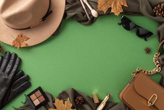 Trendy autumn accessories. Top view shot featuring a fashionable felt hat, cozy scarf, stylish gloves, sunglasses and a statement handbag on green background. Perfect for advertising campaigns