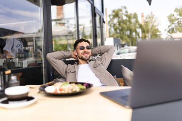 Relaxed happy businessman at desk cafe table calm man relax break hold hand behind head dream rest from laptop