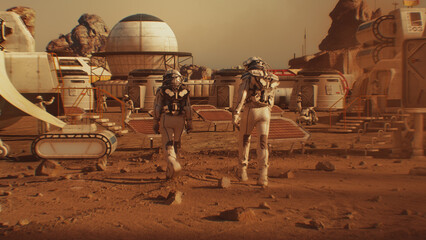 Two astronauts in spacesuits walk toward research station, colony or scientific base on Mars. Solar cell and panels. Space mission on red planet. Futuristic colonization and space exploration concept. © Framestock