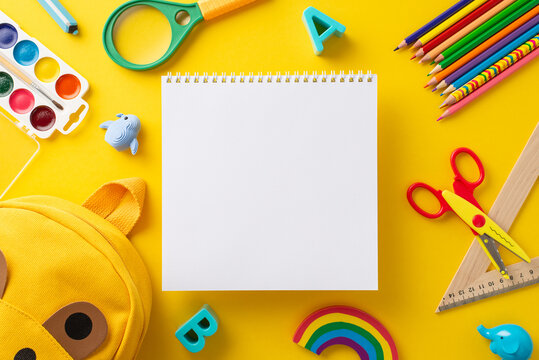 Captivate parents and educators with striking top view photo of blank notepad page brimming with vibrant school supplies on yellow isolated backdrop, an excellent choice for educational campaigns