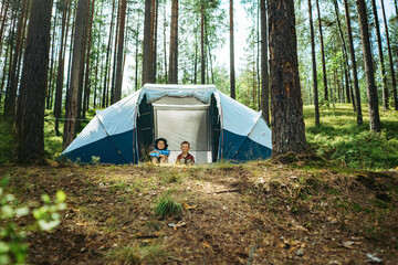 cute caucasian boys sitting inside a big touristic tent. Family camping concept