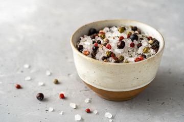 Sea salt with spices in small bowl on concrete background. Copy space for text
