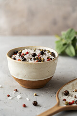 Sea salt with spices in small ceramic bowl, spoon with salt, sage behind over concrete background. Copy space for text