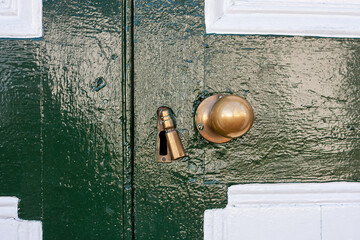 close up of a brass door knob and keyhole on a green and white door