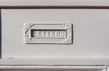 Decorative mail slot in a white door