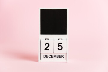 Christmas, wooden calendar with the date December 25 on a pink background. Christmas and New Year celebration concept.
