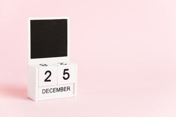 Christmas, wooden calendar with the date December 25 on a pink background. Christmas and New Year celebration concept.