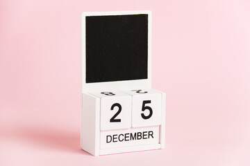 Christmas, wooden calendar with the date December 25 on a pink background. Christmas and New Year celebration concept.