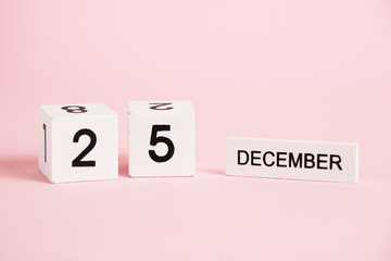 Christmas, wooden calendar with the date December 25 on a pink background. Christmas and New Year celebration concept.