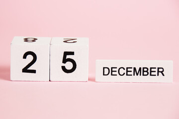 Christmas, wooden calendar with the date December 25 on a pink background. Christmas and New Year celebration concept.