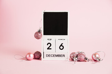 Christmas and Boxing Day, wooden calendar with December 26 date and Christmas tree decorations on pink background. Christmas and New Year celebration concept.