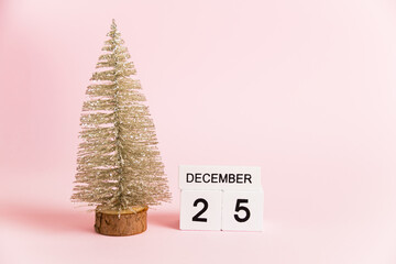 Christmas decoration and calendar with date December 25 on pink paper background with copy space. Christmas and New Year celebration concept.