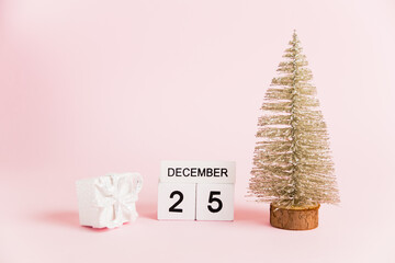 Christmas decoration and calendar with date December 25 on pink paper background with copy space. Christmas and New Year celebration concept.