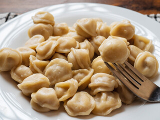 Big portion of Russian dumplings on a white plate. Tasty dinner. Classic west European dish.