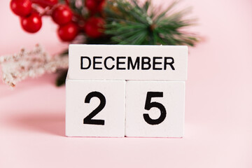 Christmas decoration tree branch and calendar with date December 25 on pink paper background with copy space. Christmas and New Year celebration concept.