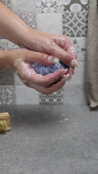 Mujer lav&aacute;ndose las manos con una pastilla de jab&oacute;n natural en una ducha con alicatado de azulejo