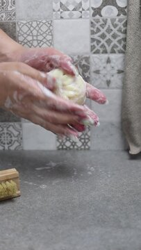 Mujer lav&aacute;ndose las manos con una pastilla de jab&oacute;n natural en una ducha con alicatado de azulejo