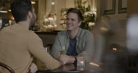 Gay Couple on a Date in Bar Restaurant in the Evening, Holding hands
