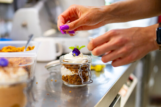 Woman Chef Hand Decorated Carrot Cake In A Glass Jar On Table